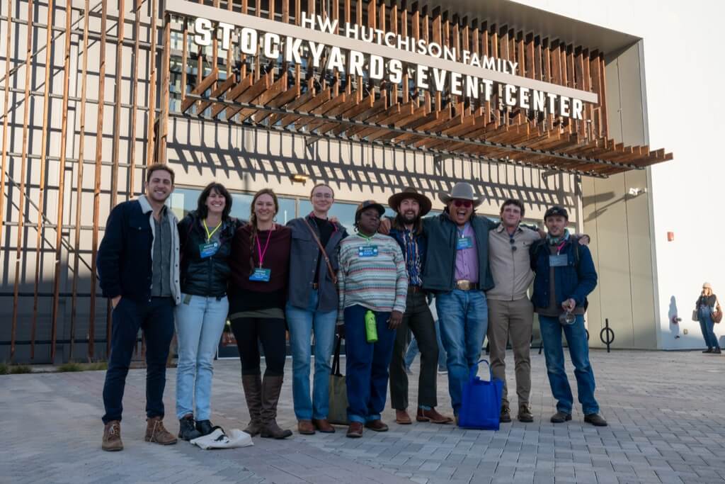 A group of people posing outside a building with the sign saying Stockyards Event Center